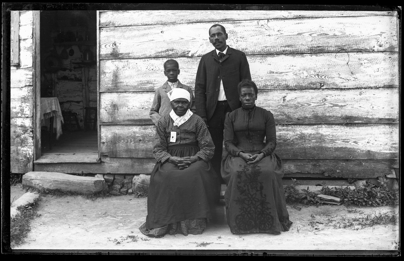 A family portrait believed to include Louisa Mahoney, seated at front left, outside a wooden house