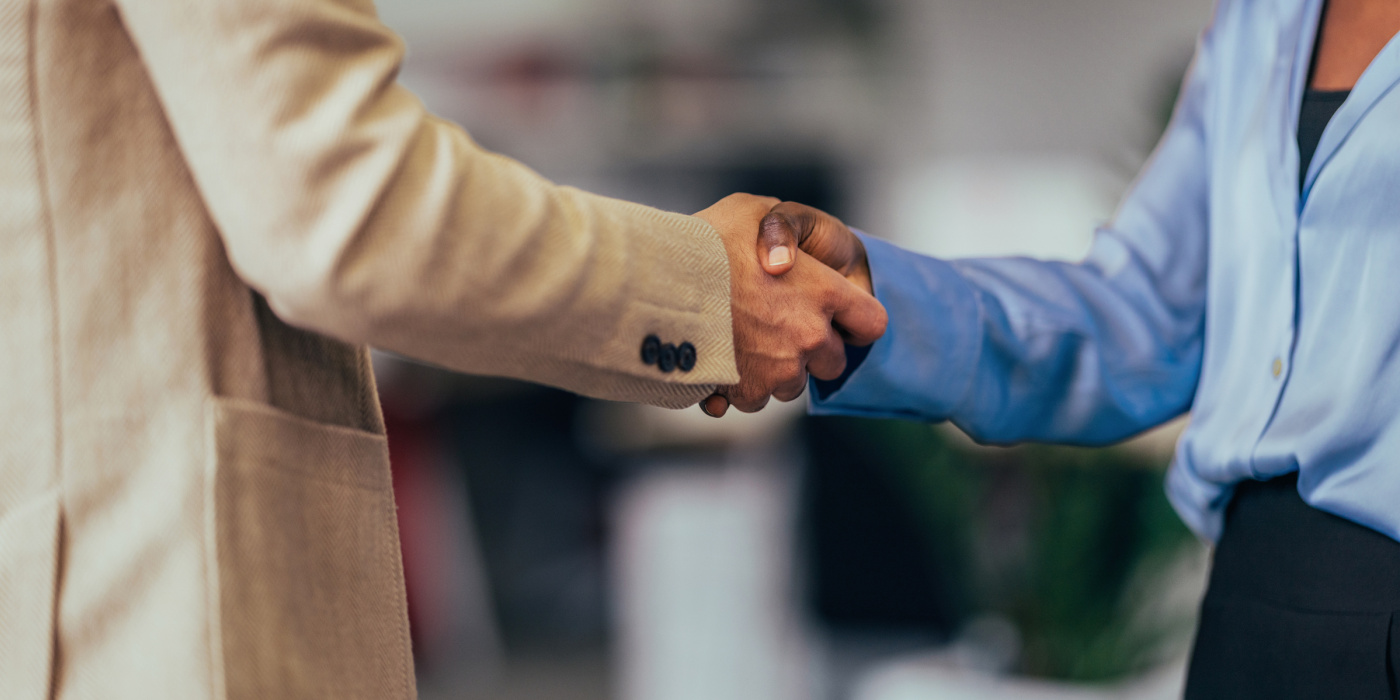 A close-up photo capturing a professional handshake between business colleagues in a well-lit office setting. 