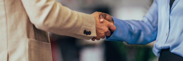 A close-up photo capturing a professional handshake between business colleagues in a well-lit office setting. 
